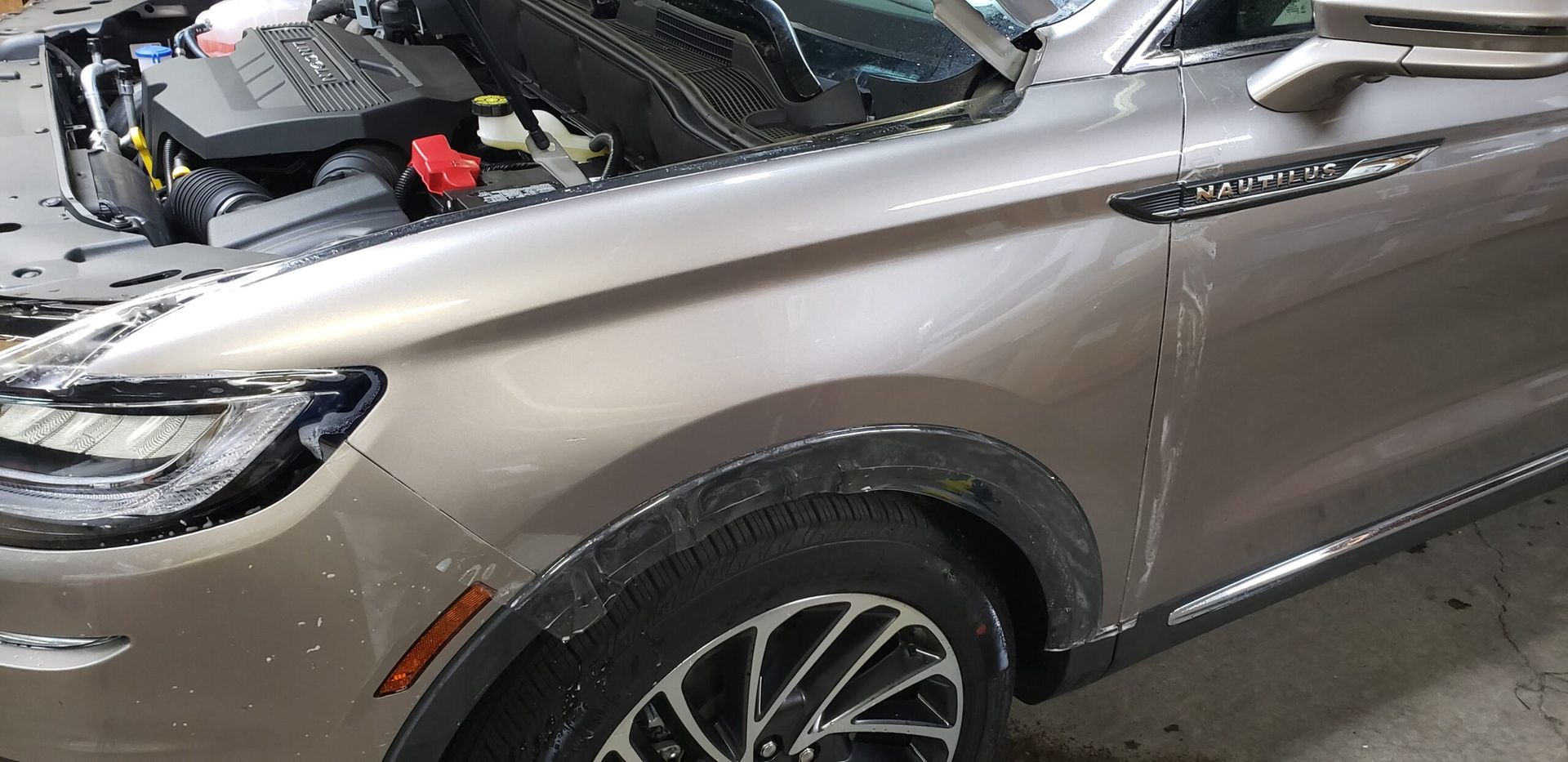 Silver SUV with hood open in an auto shop garage