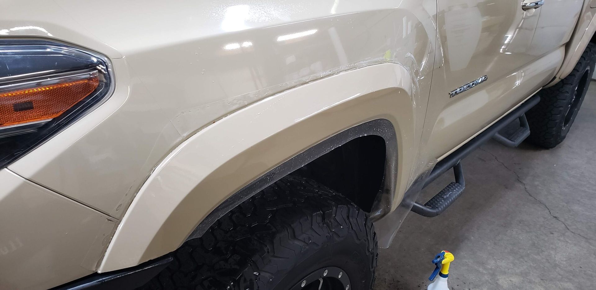 Beige pickup truck side panel and front wheel in a garage