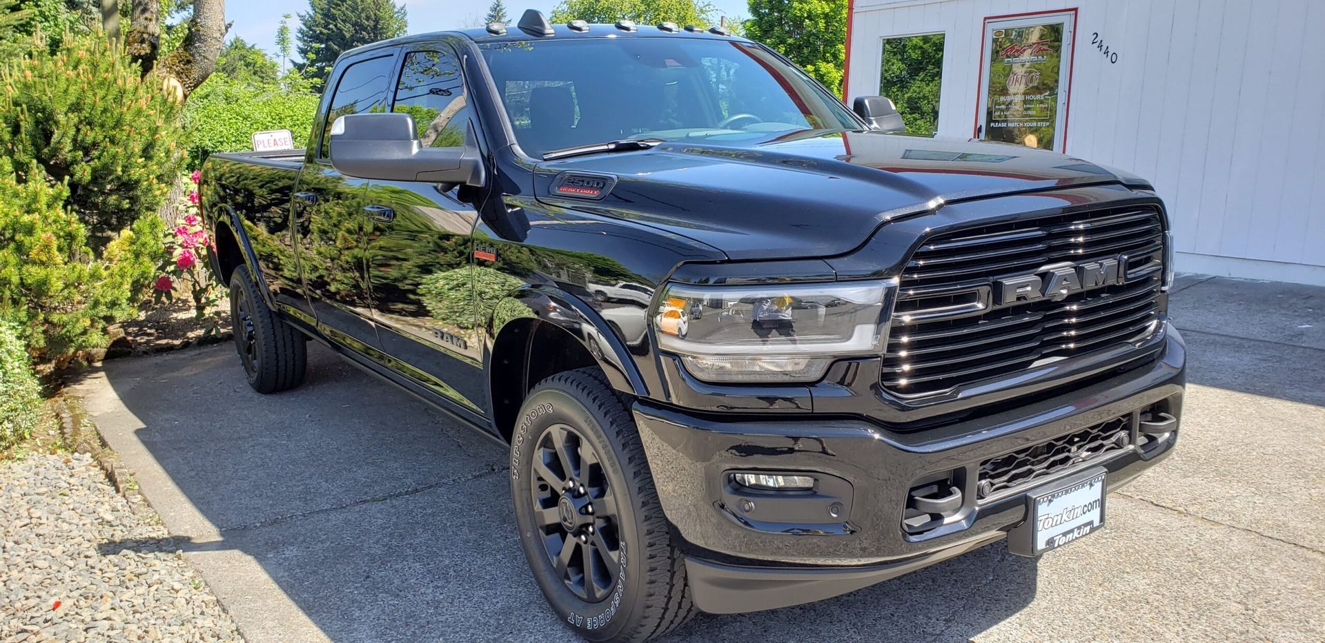 Black pickup truck parked in a driveway beside a white house and shrubs