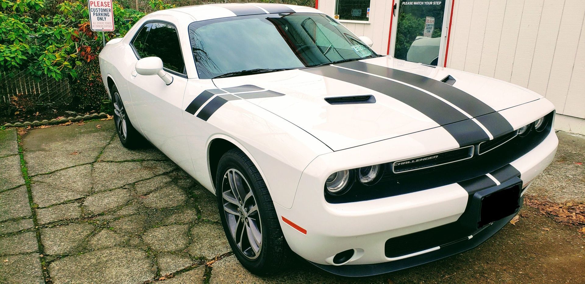 White sports car with black racing stripes parked on a driveway