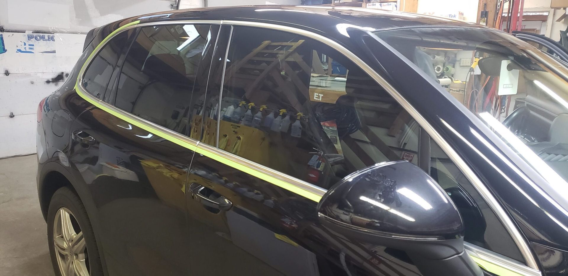Black SUV with a bright yellow stripe along the side, parked indoors in a garage