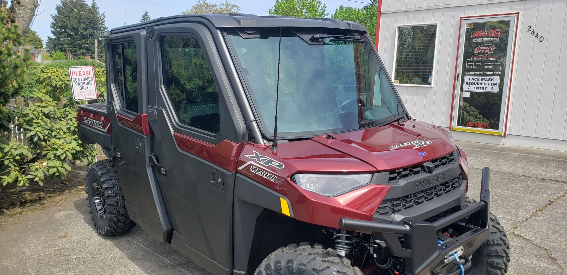 Black UTV with red accents parked outside a building, angled front view