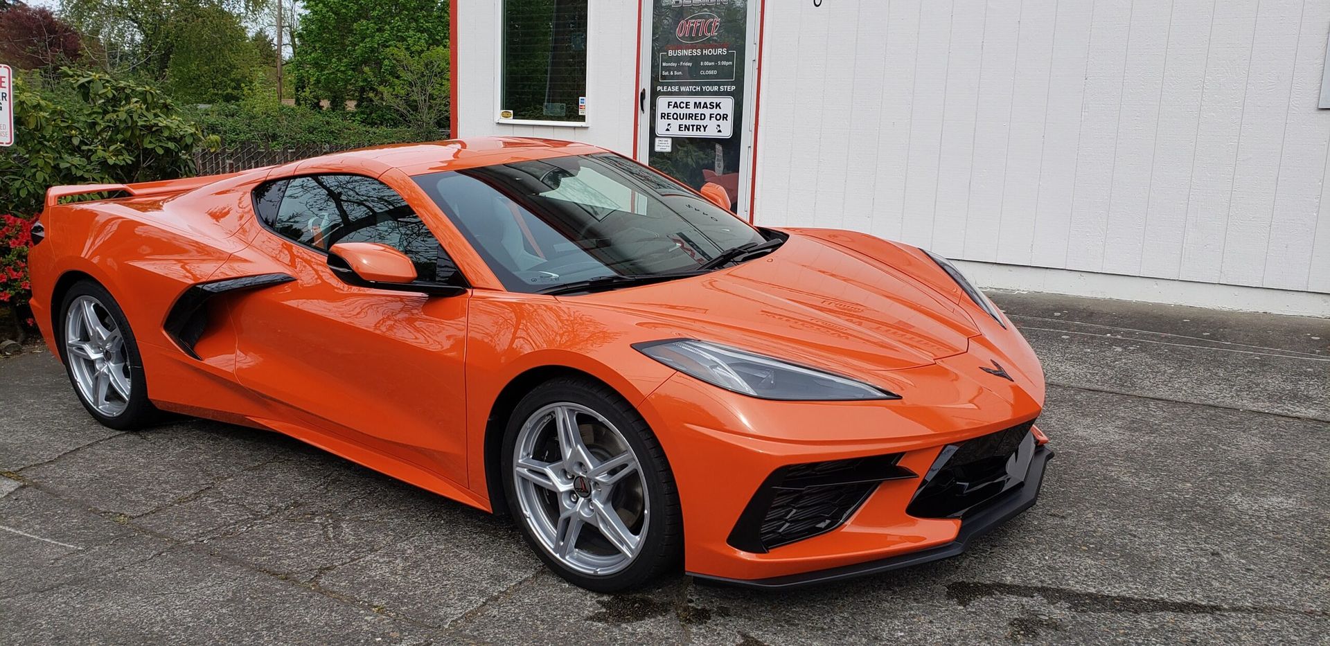 Orange sports car parked outside a building on a wet pavement