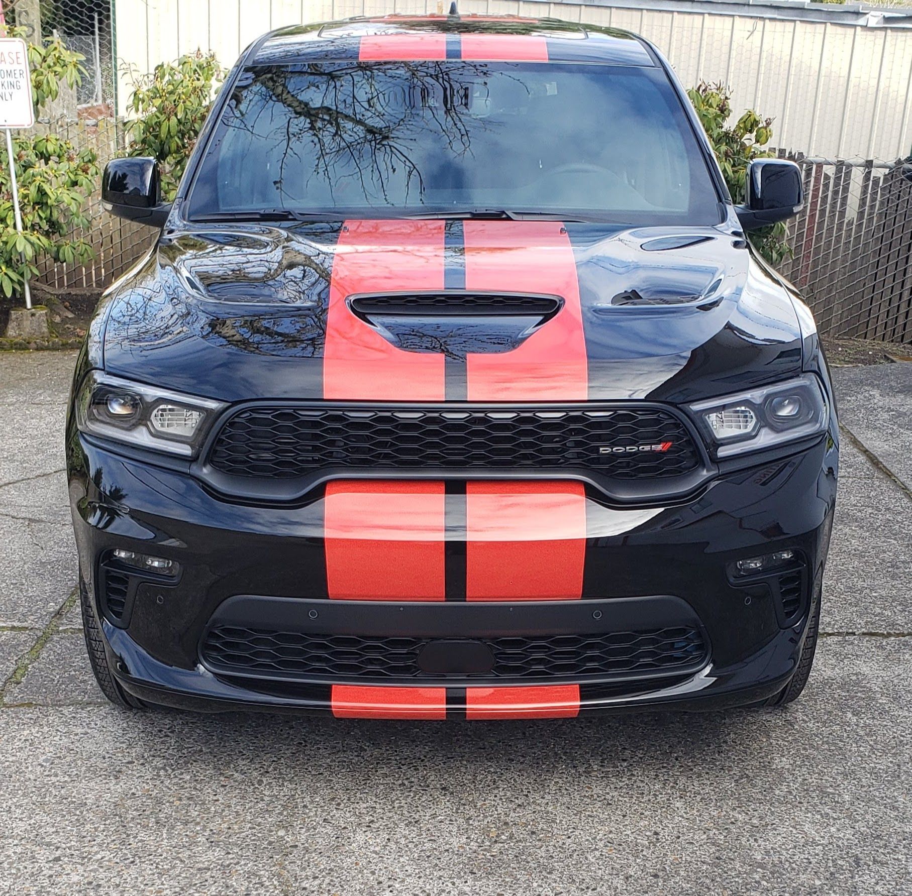 Front view of a black car with a red racing stripe parked outdoors.
