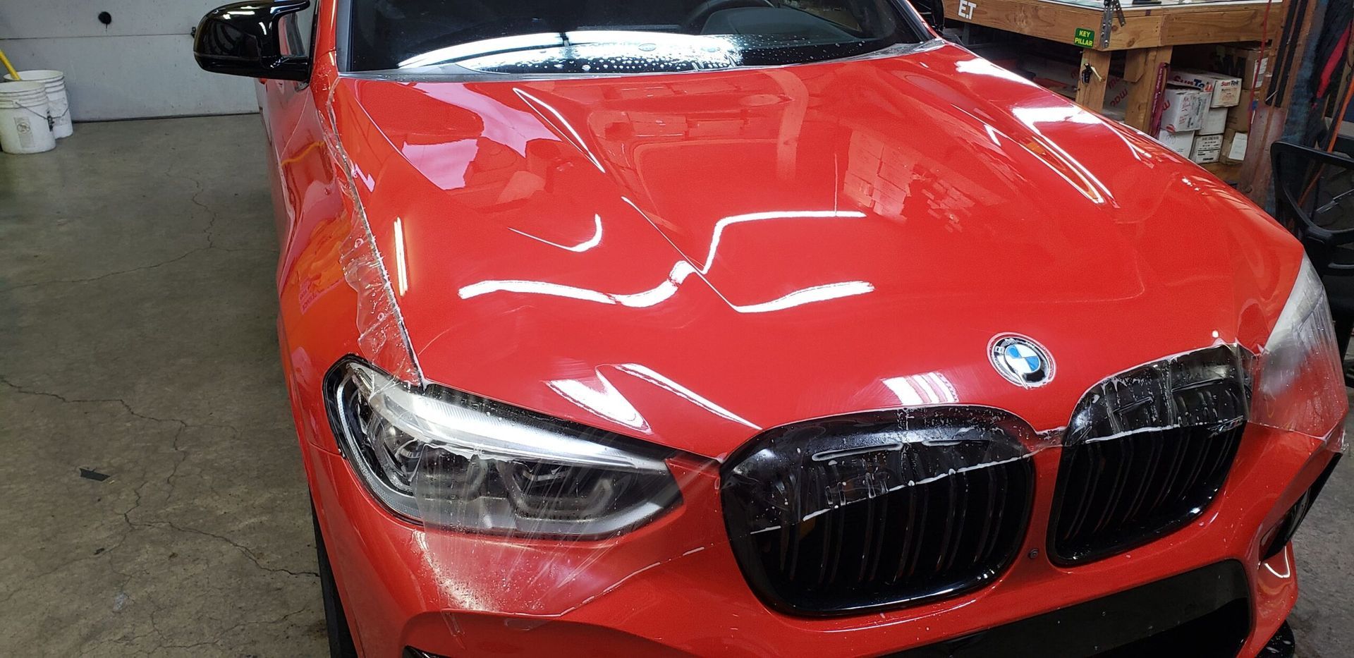 Red BMW sedan in a garage, front view with hood and grille visible