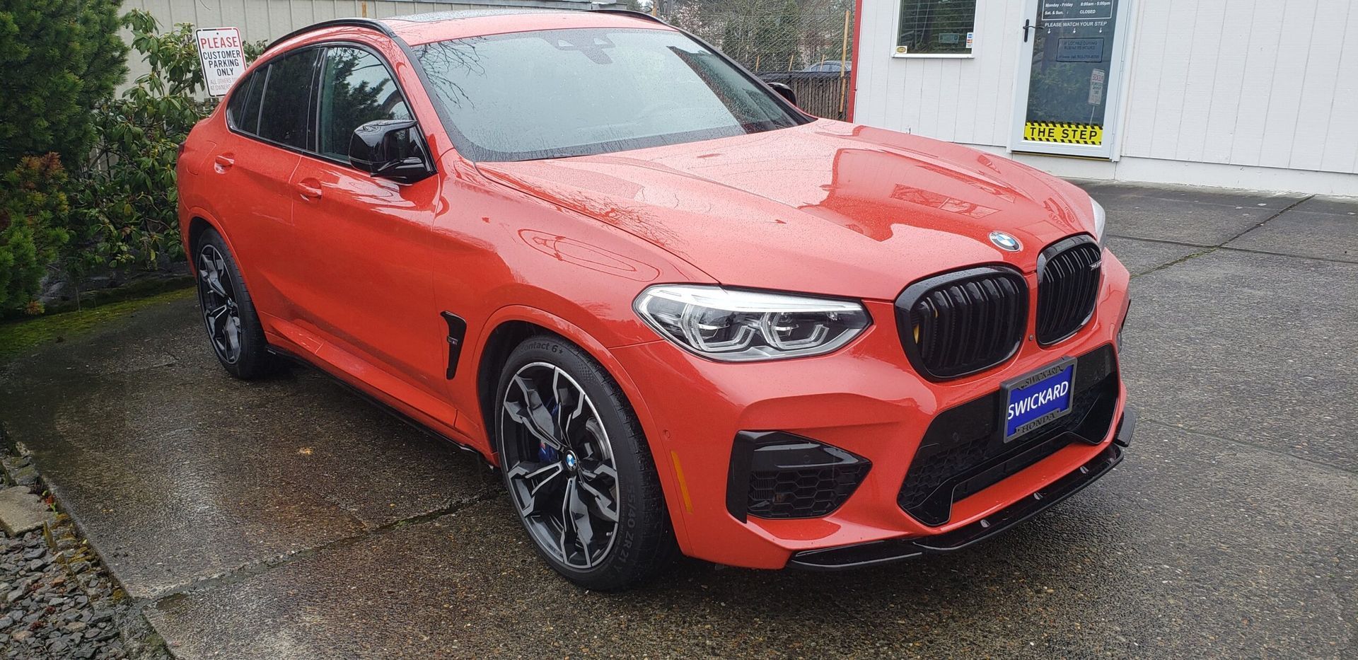 Orange BMW SUV parked outside a building on a wet street