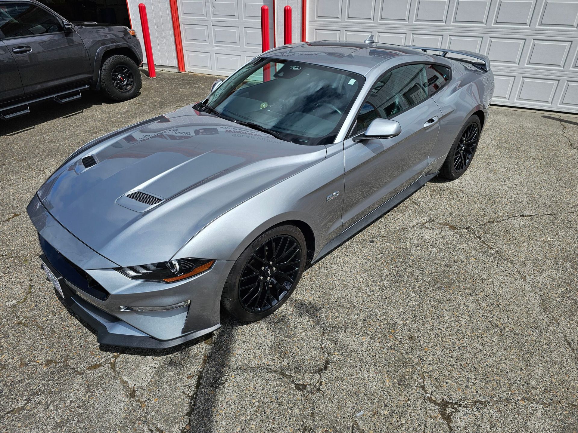 Silver sports coupe parked on a driveway in front of a garage