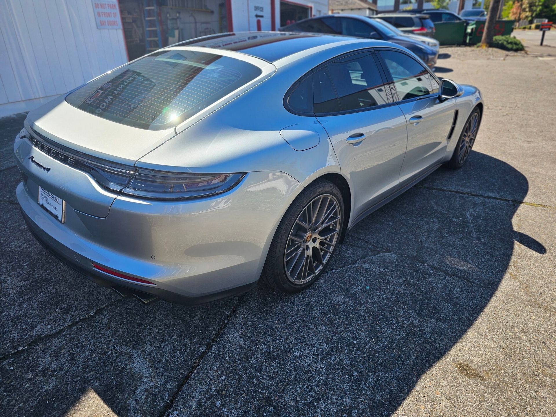Silver sports sedan parked outdoors on a sunny lot, shown from the rear-left side.