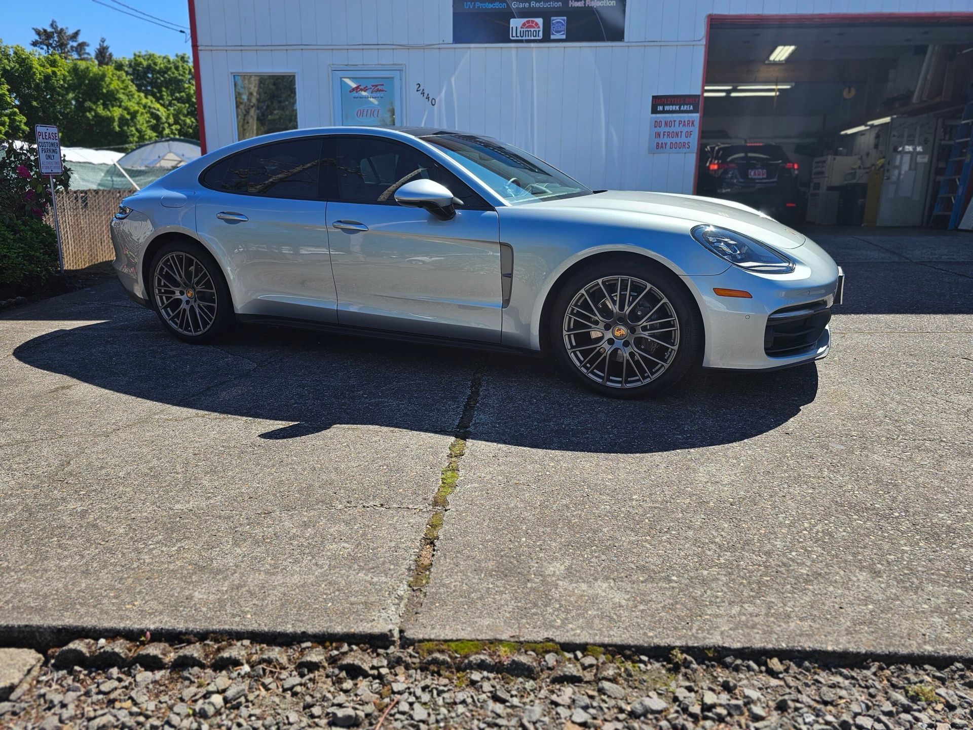 Silver sports coupe parked outside an auto shop on a sunny day.