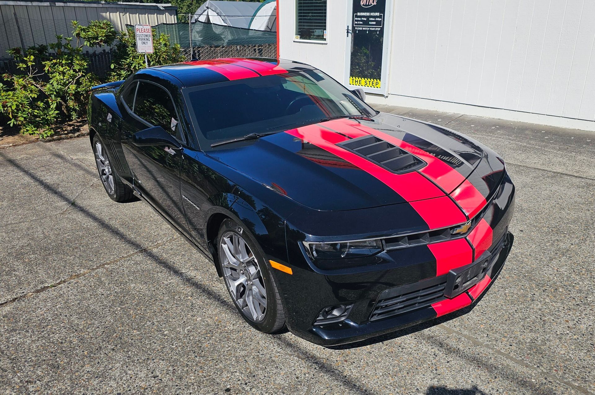 Black sports car with red racing stripes parked on a driveway outdoors