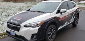 White compact SUV with black accents and red decals parked on a wet road