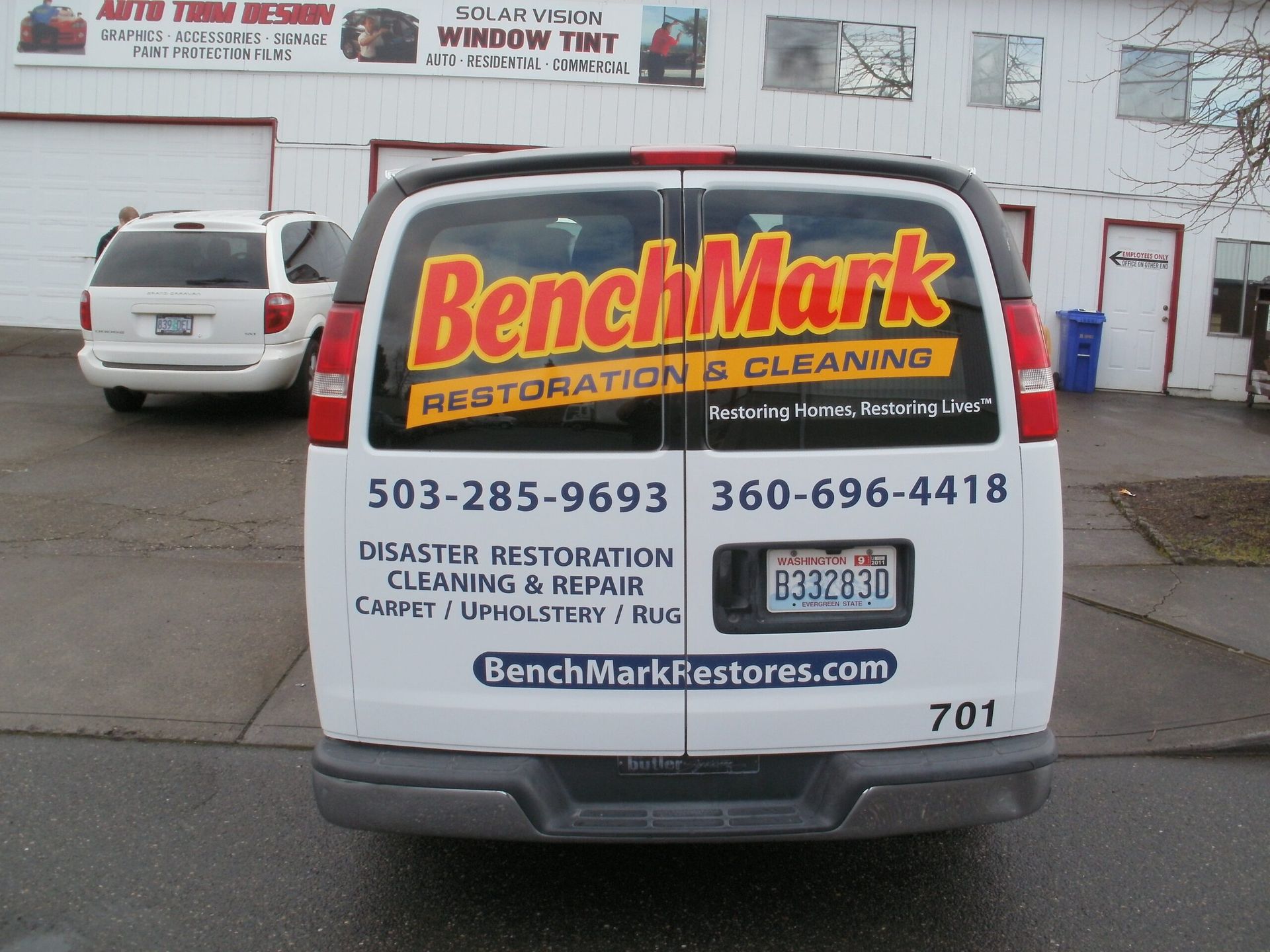 BenchMark Restoration & Cleaning van parked outside a service building, rear view with company contact info.