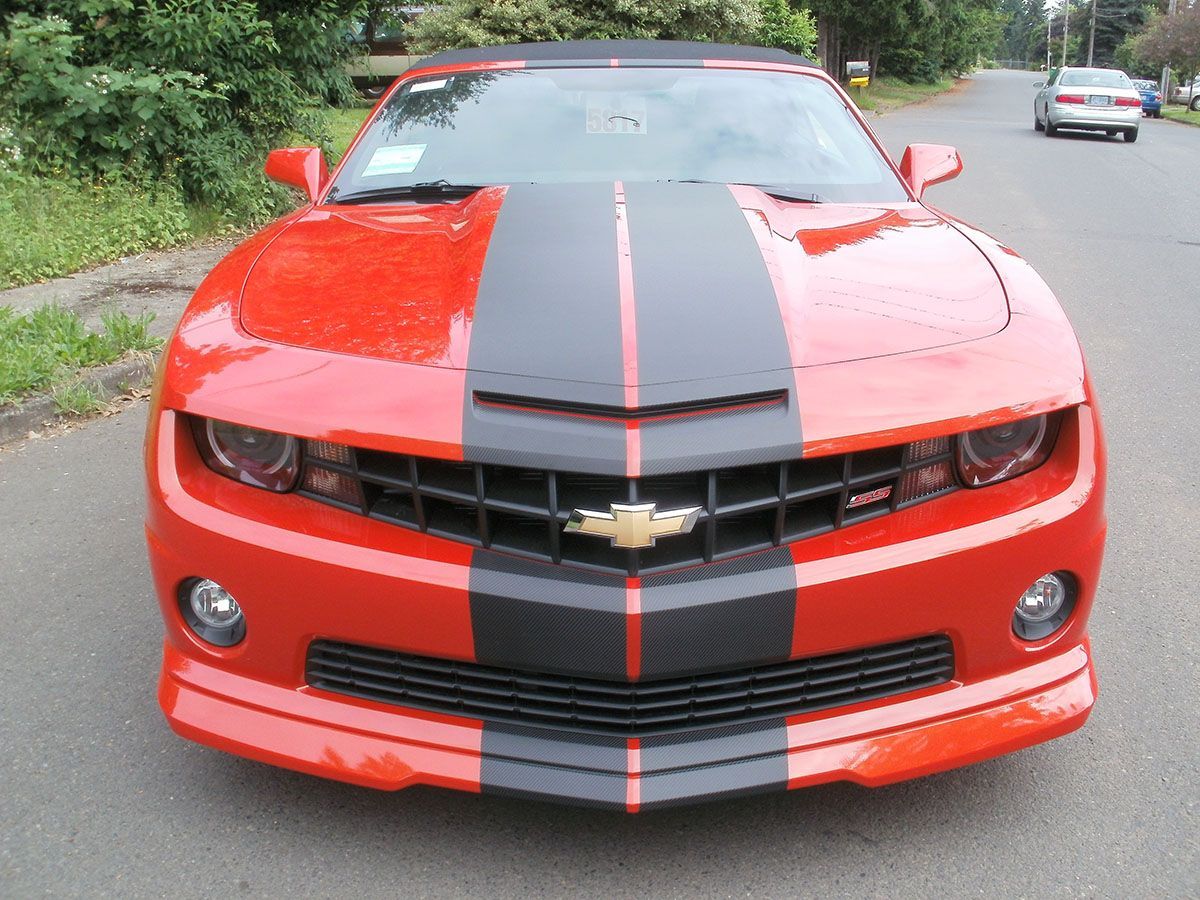 Red sports car with black racing stripe parked on a street