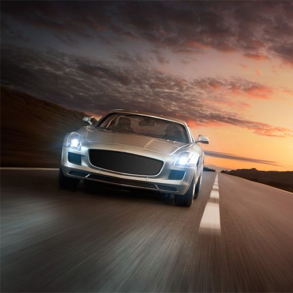 Silver sports car speeding on an open road at sunset