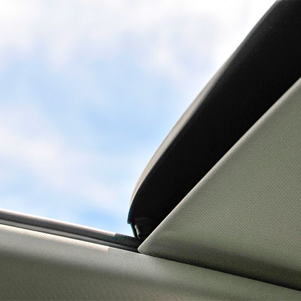 Car sunroof partially open, showing blue sky above a gray interior.