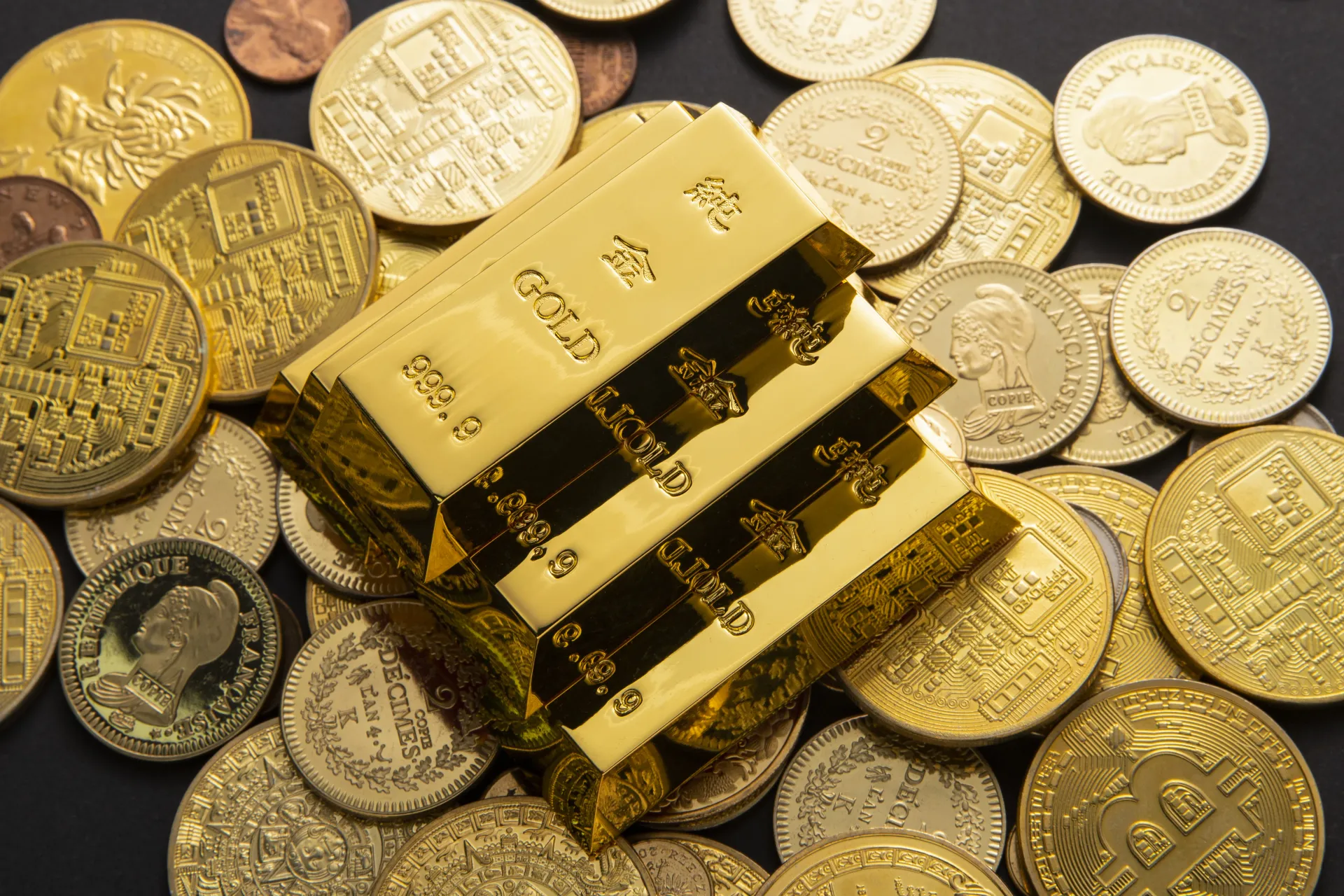 Gold bars stacked on assorted gold and silver coins, symbolizing wealth and investment