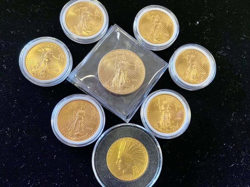 Eight gold coins in protective cases arranged on a dark surface.