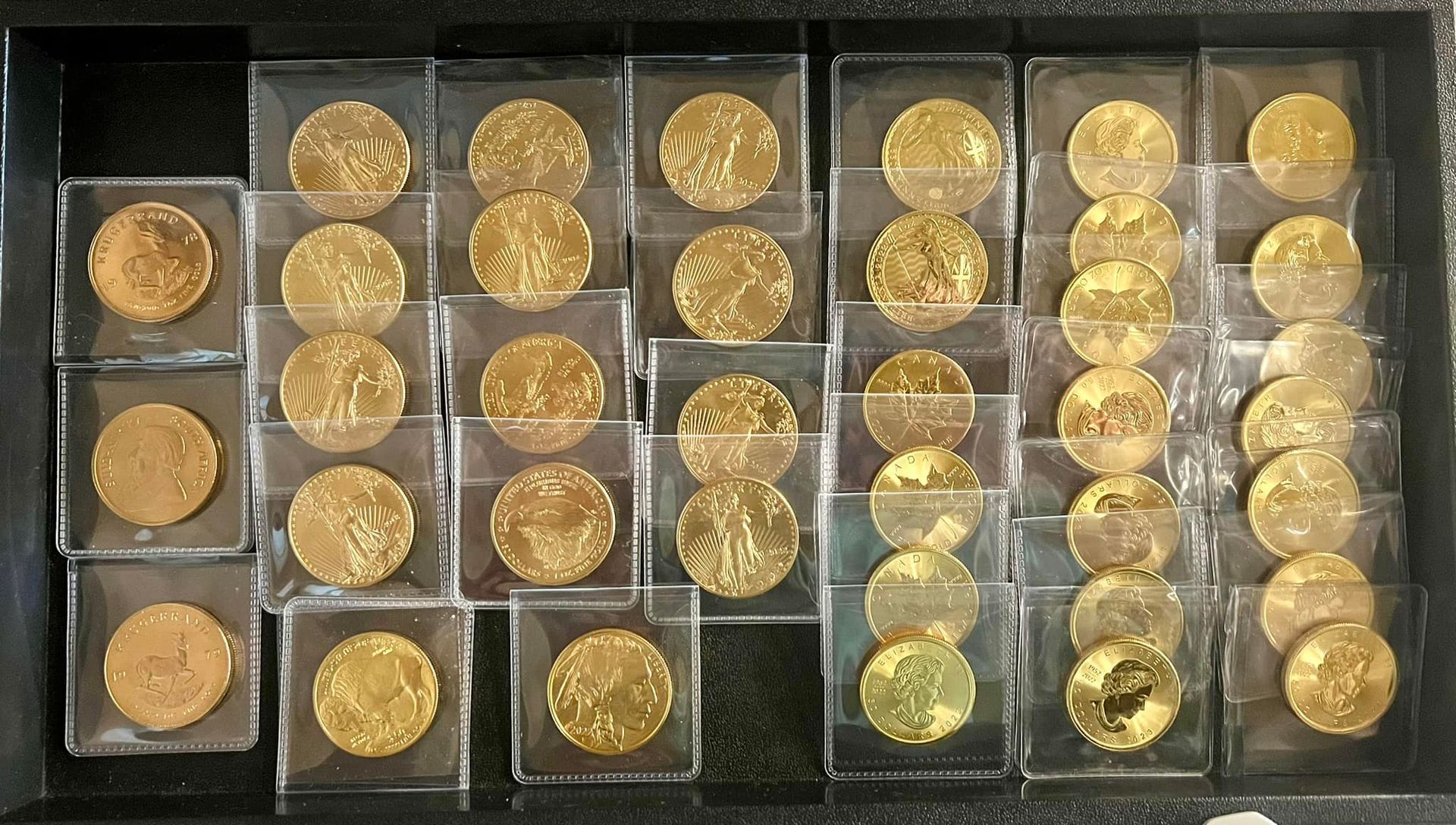 Gold coins in plastic holders displayed in a black tray.