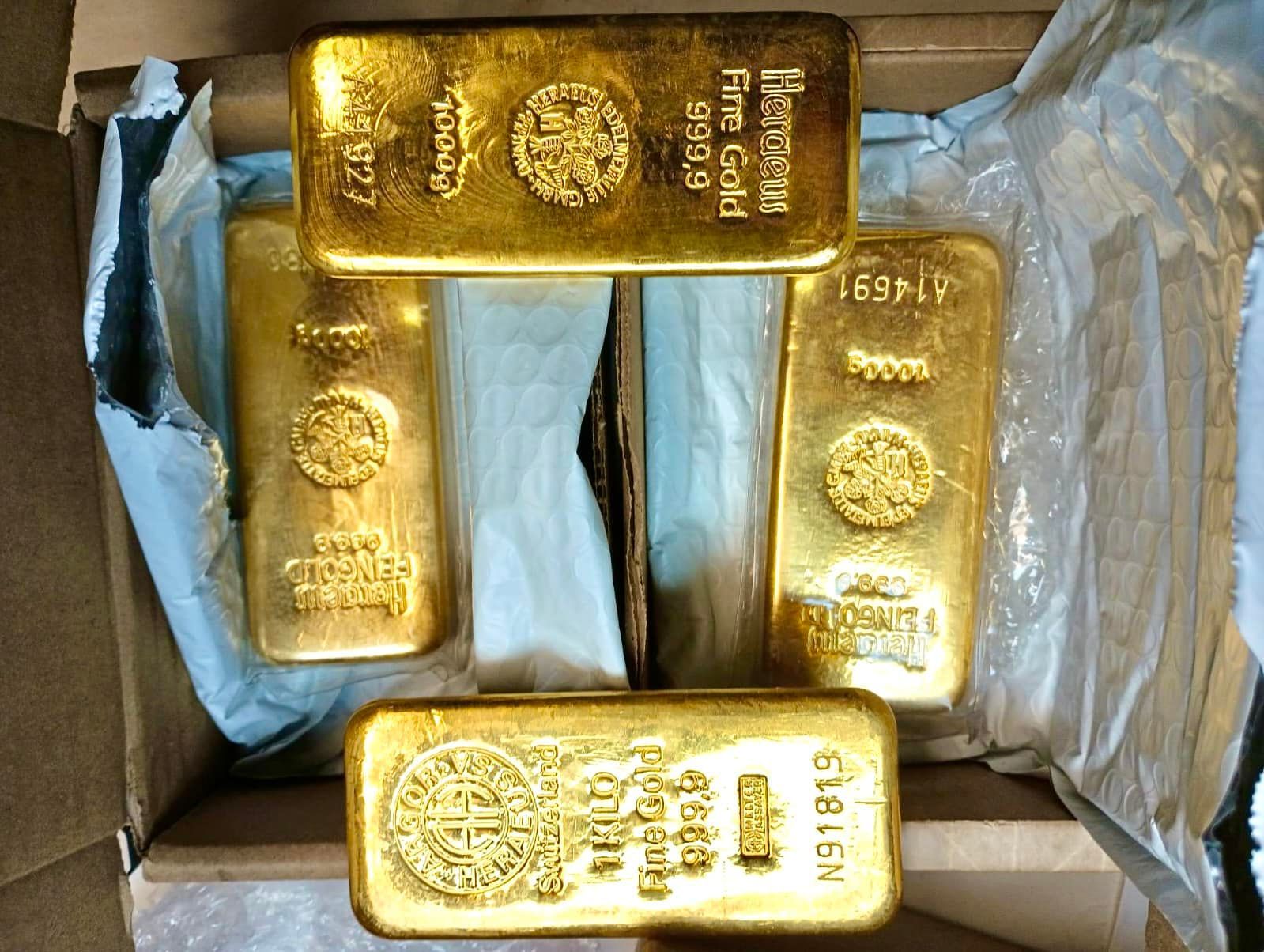 Five gold bullion bars in a cardboard box, labeled