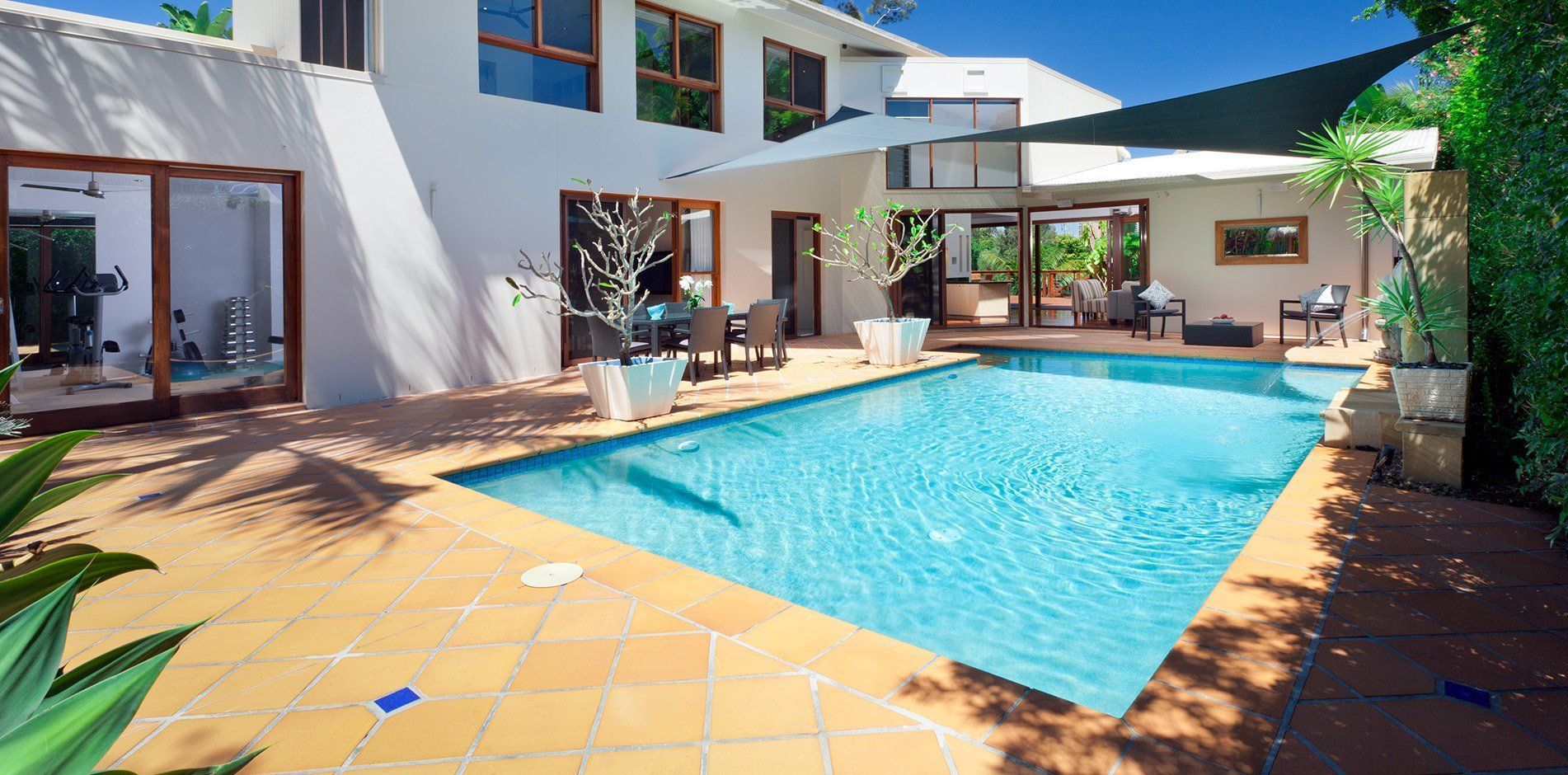 There is a large swimming pool in the backyard of a house.