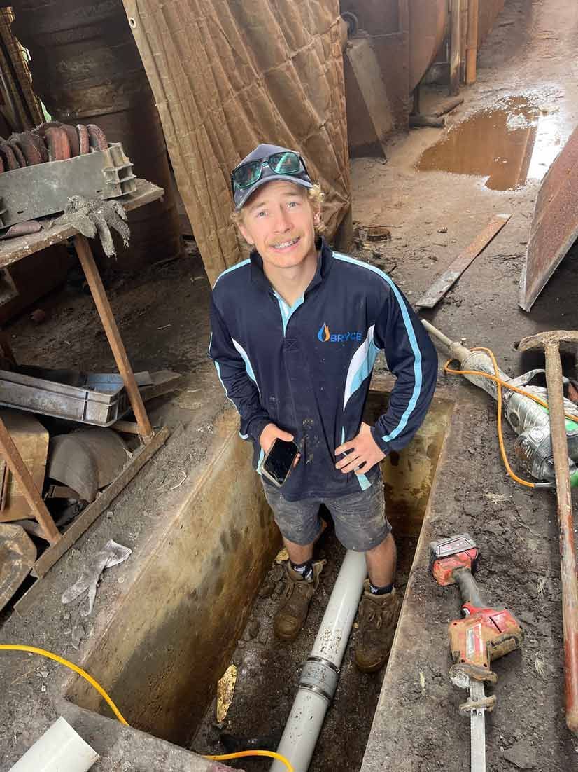 A Man is Fixing a Pipe — Wello's Plumbing & Gas In Thurgoona, NSW