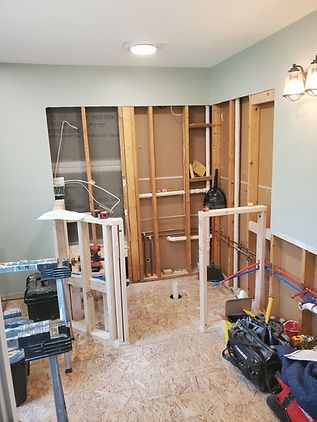 Partially gutted room under renovation with exposed wall studs, tools, and construction materials on the floor