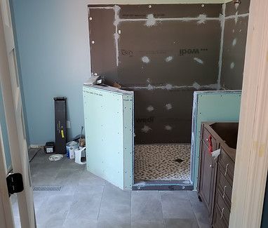 Renovation in progress in a bathroom, with unfinished walls, floor debris, and a bathtub under construction.