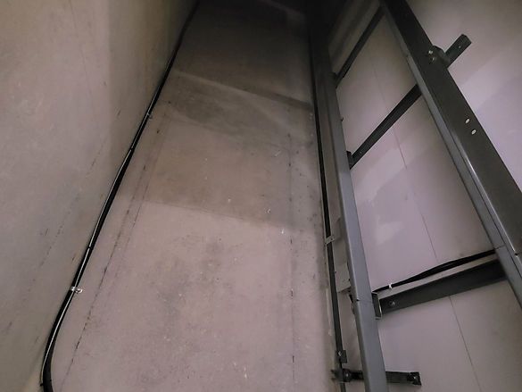 Upward view of a narrow concrete shaft or stairwell with metal rails on both sides