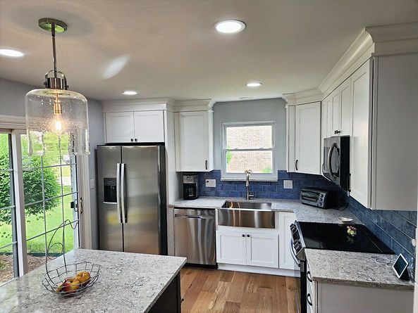 Bright modern kitchen with white cabinets, stainless steel appliances, and blue tile backsplash.