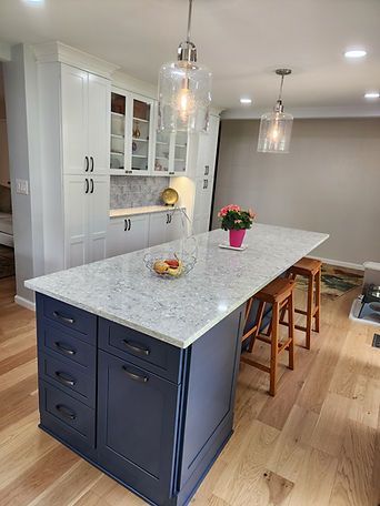 Modern kitchen with navy island, white cabinetry, pendant lights, and wooden stools