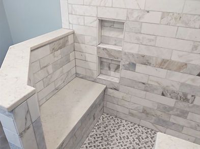 Empty tiled shower with built-in bench and recessed shelves.