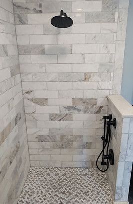 Tiled walk-in shower with black rain showerhead and patterned tile floor
