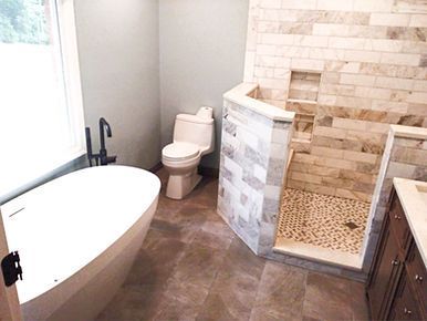 Modern bathroom with freestanding tub, toilet, and tiled walk-in shower