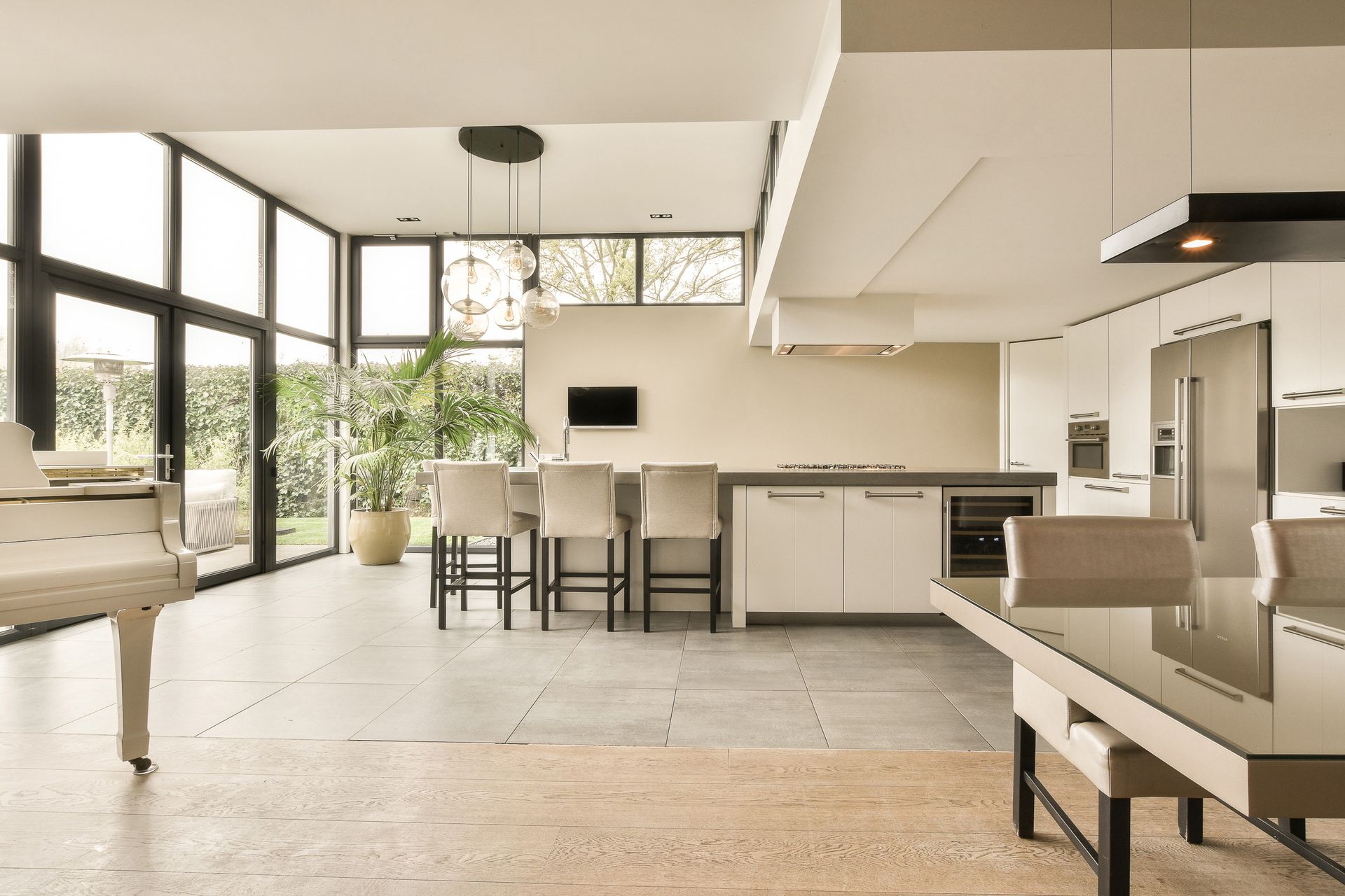Bright modern living-dining room with large windows, white furniture, and a kitchen island.