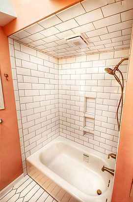 White tiled walk-in shower with bathtub and handheld showerhead