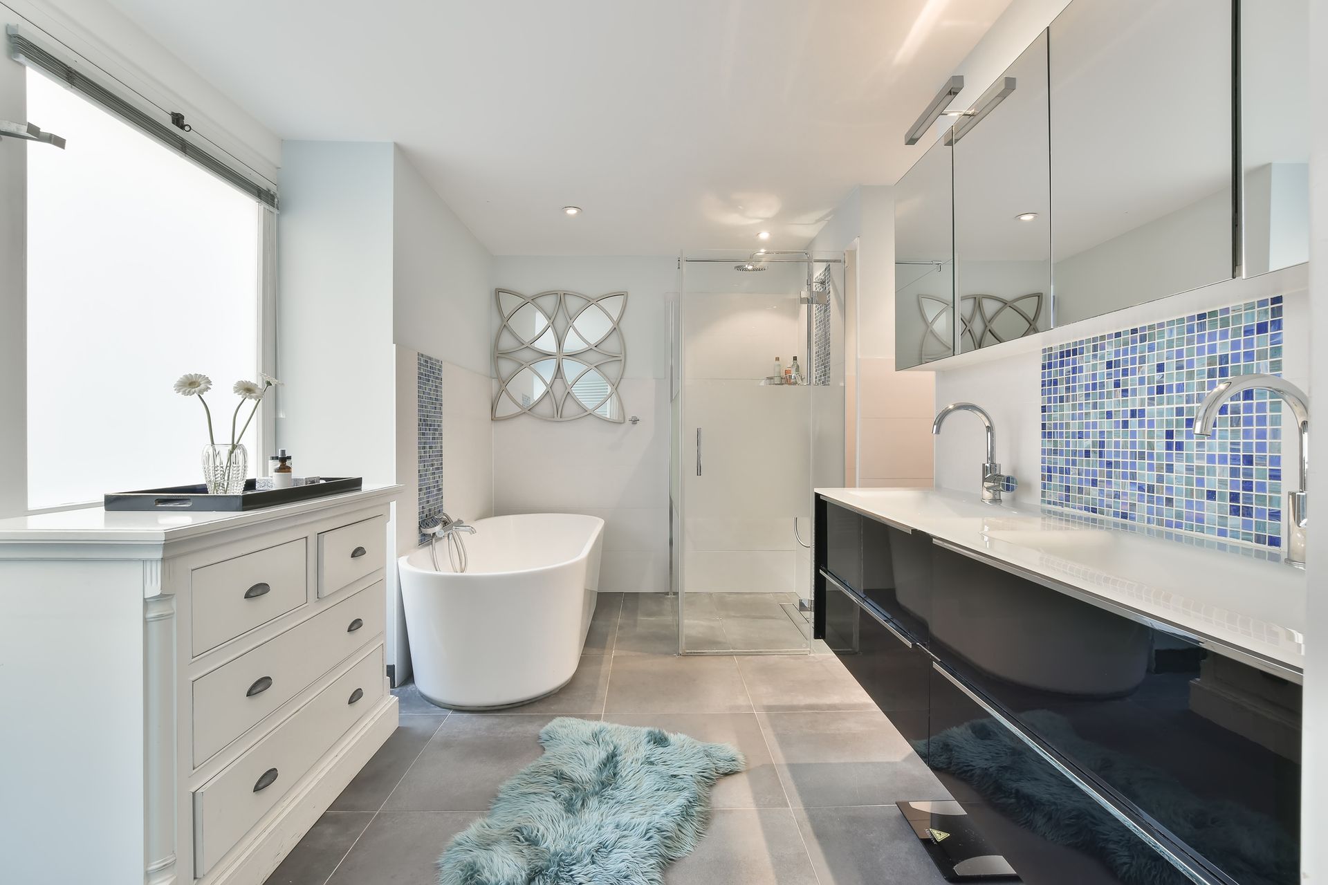 Modern white bathroom with freestanding tub, double vanity, mosaic backsplash, and large mirror