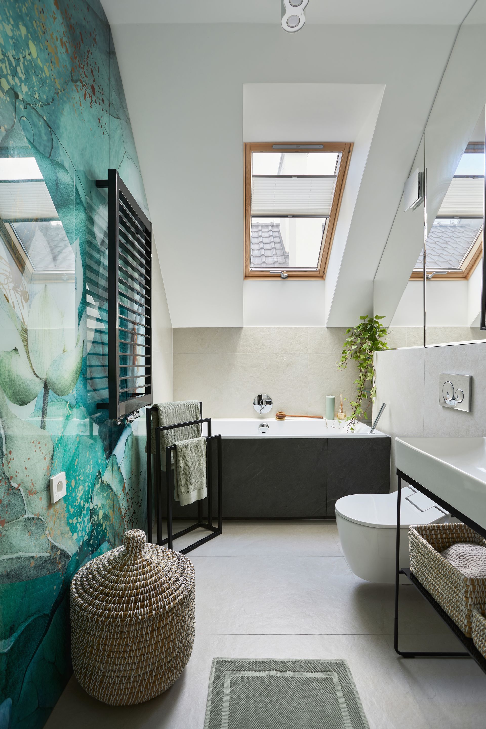 Modern bathroom with teal mural wall, skylights, dark vanity, and freestanding tub