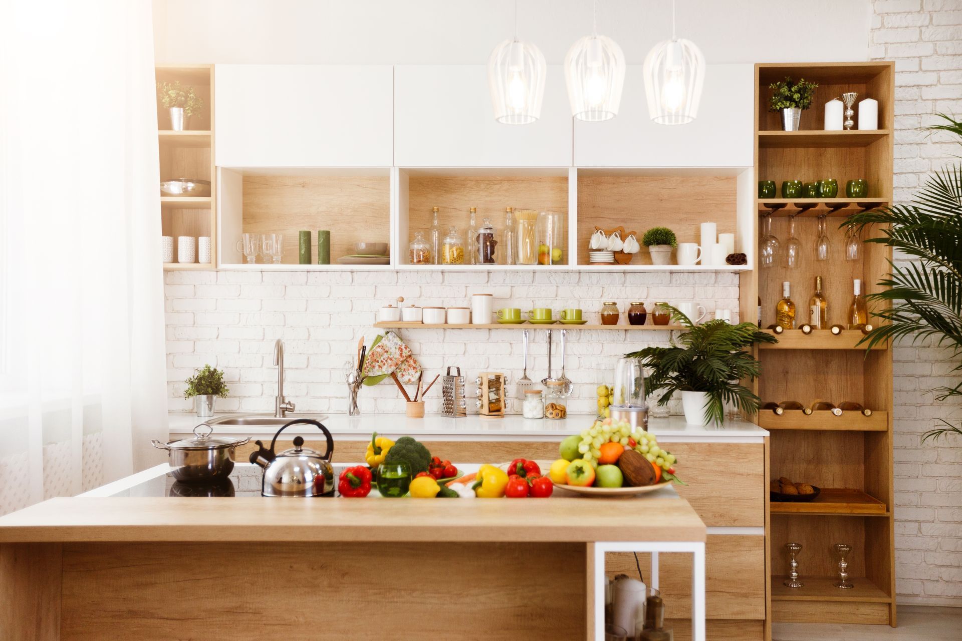 Bright modern kitchen with white cabinets, wooden shelves, island, and fruit on the countertop