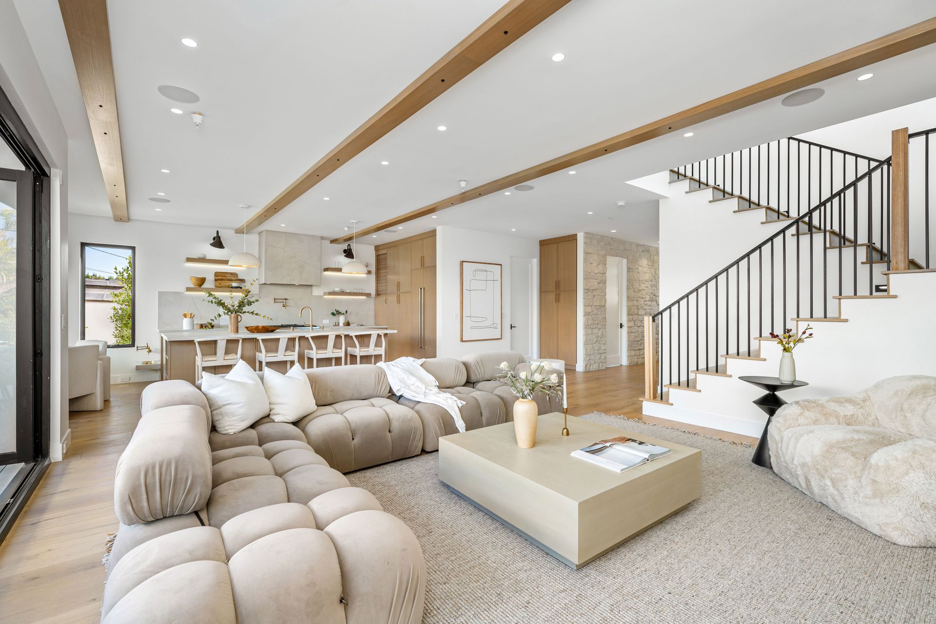 Bright modern living room with sectional sofa, staircase, and open kitchen area