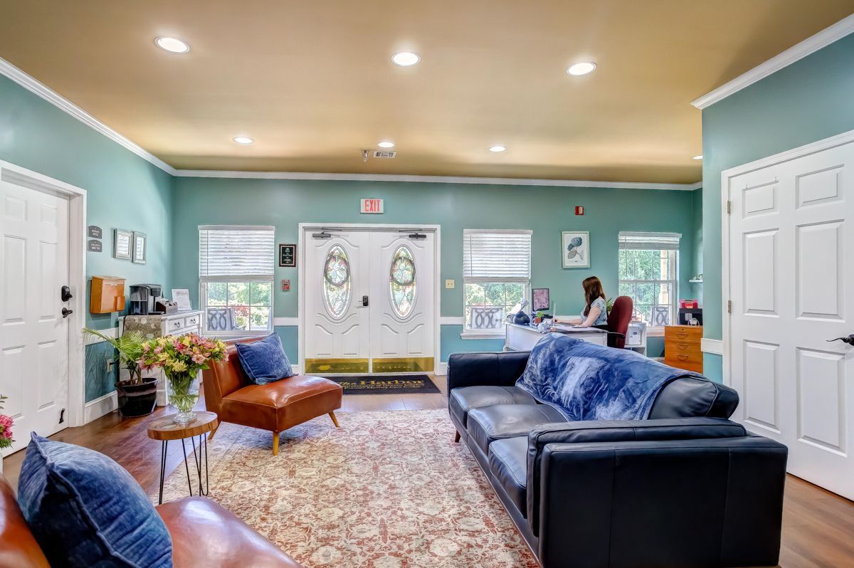 A living room filled with furniture and a woman sitting at a desk.