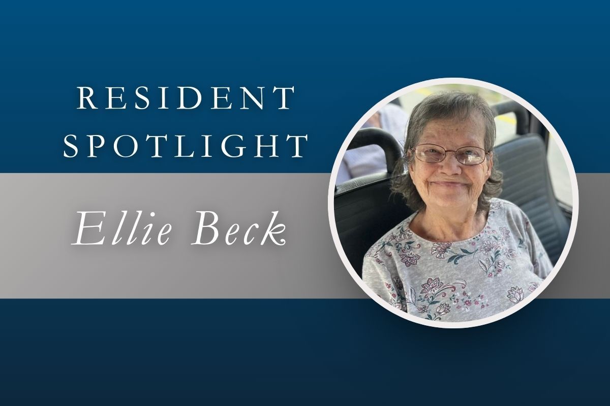 Resident spotlight featuring Ellie Beck. Elderly woman wearing glasses, smiling, seated in a vehicle.