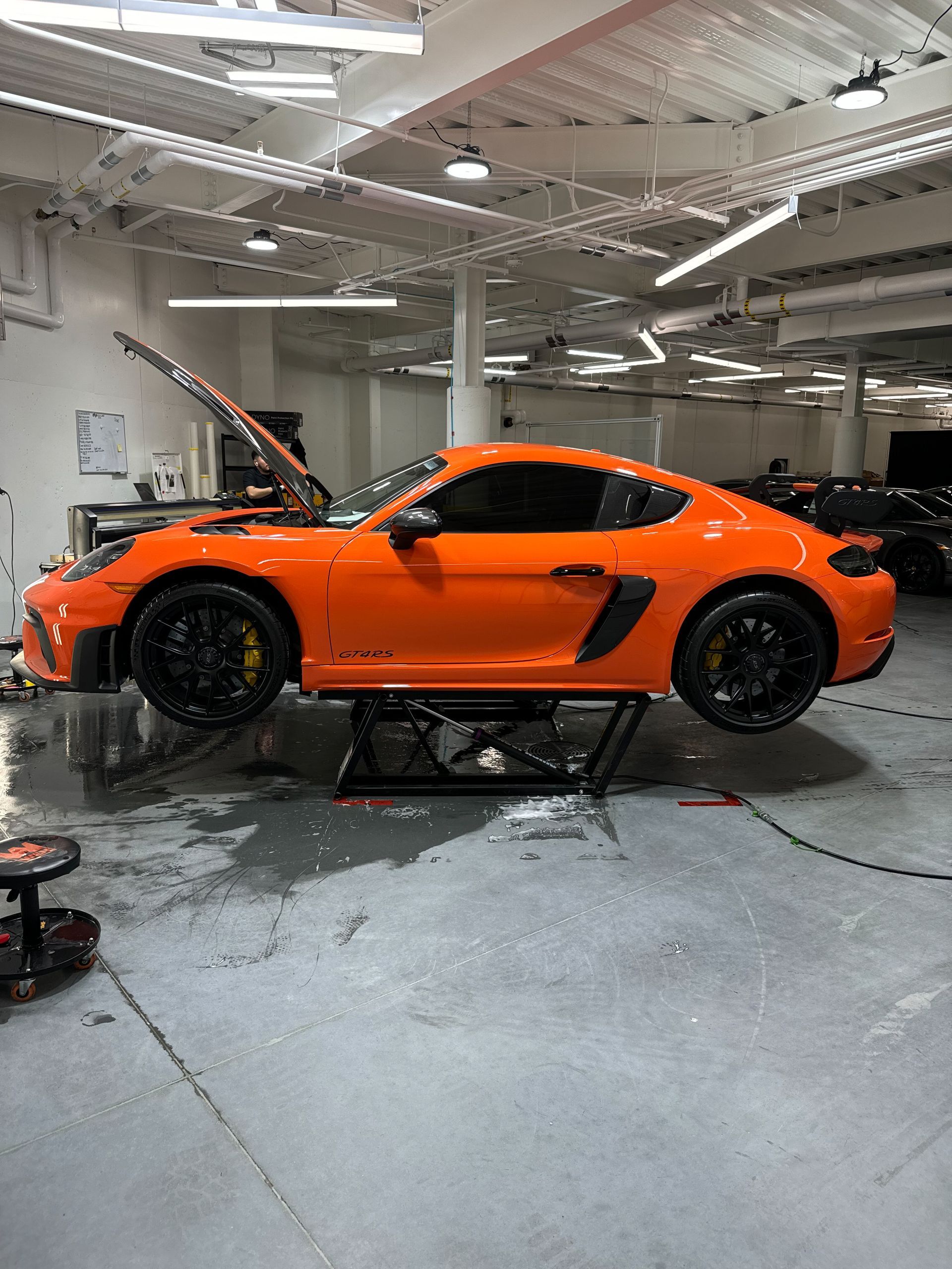 An orange sports car is parked on a lift in a garage.