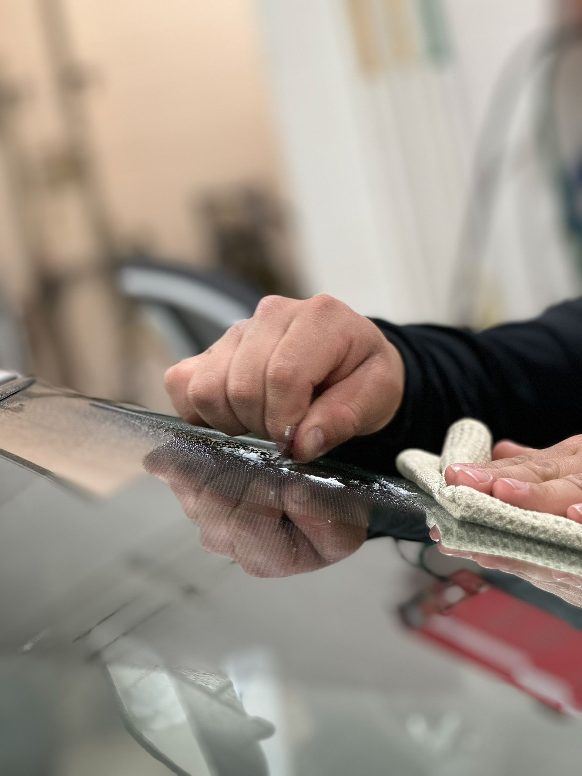 A person is cleaning a car windshield with a cloth.
