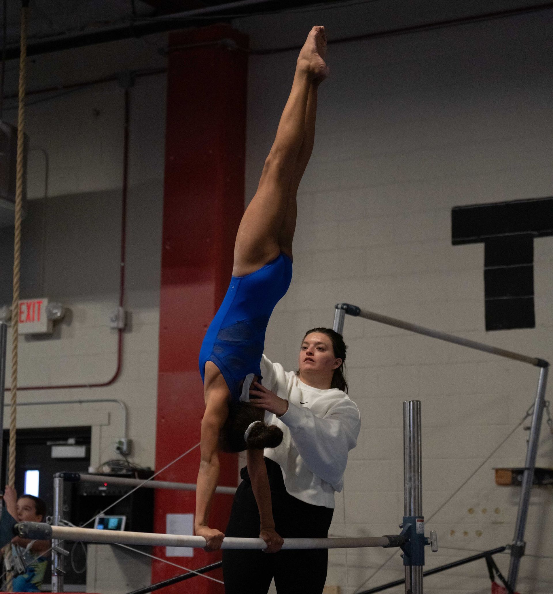 A female gymnast is balancing on a balance beam.