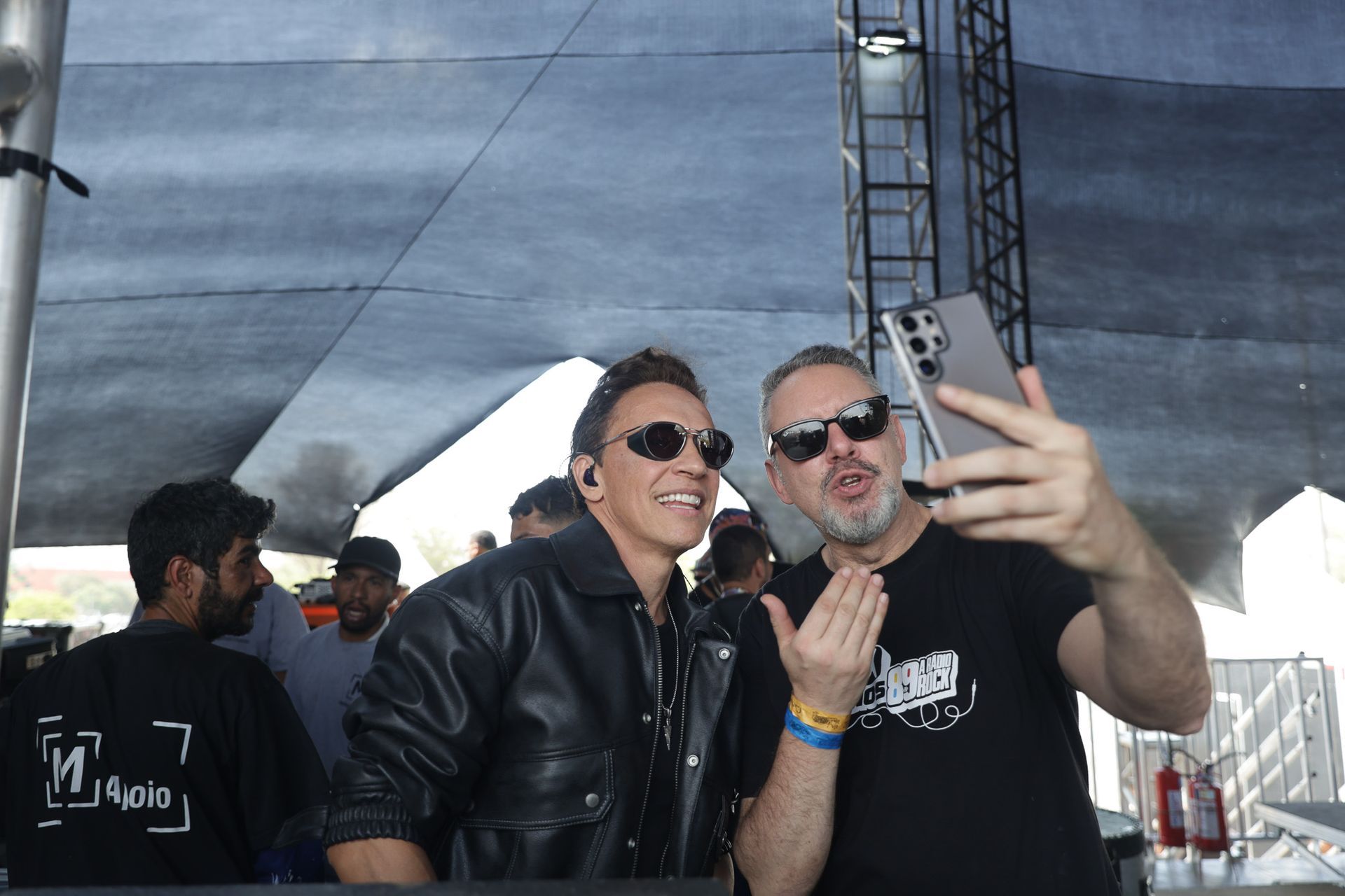 Dois homens tirando uma selfie com um smartphone ao ar livre.