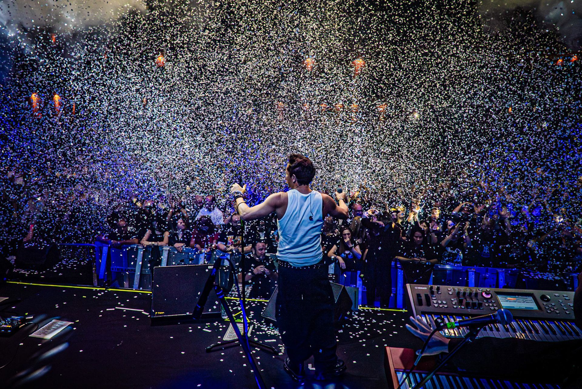 DJ se apresentando no palco diante de uma enorme multidão coberta de confete.