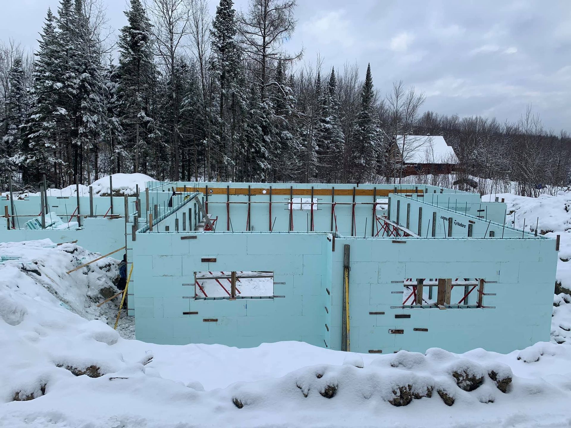 Chantier de construction avec murs en béton isolé bleu clair sous la neige.