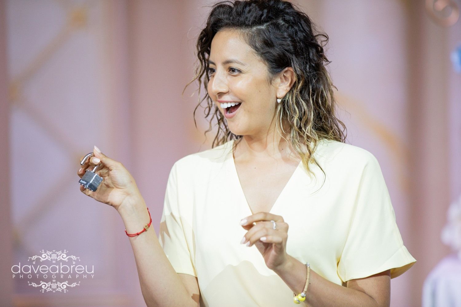 A woman in a yellow shirt is holding a small object in her hand.