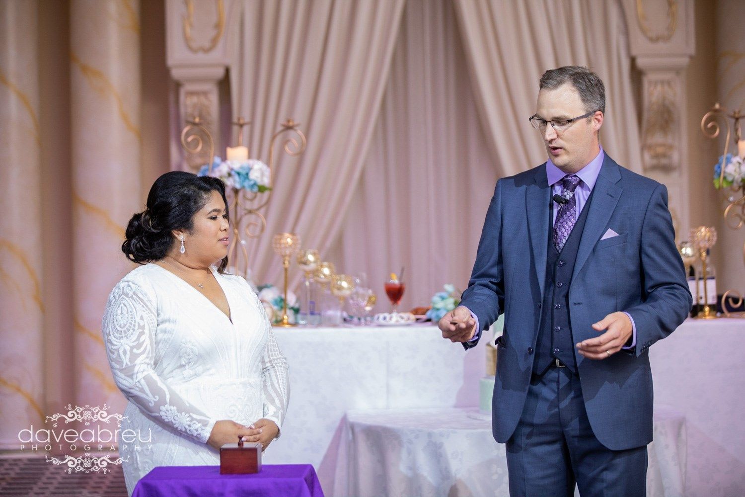A man in a suit and tie is standing next to a woman in a white dress.