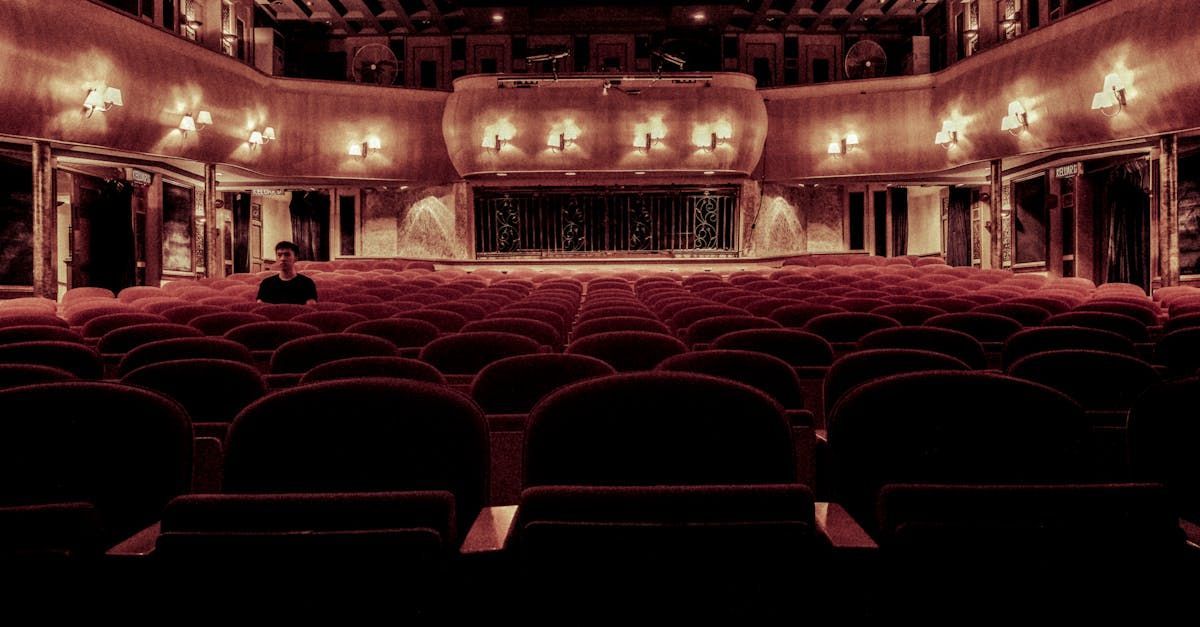 An empty auditorium with red seats and a stage in the background.